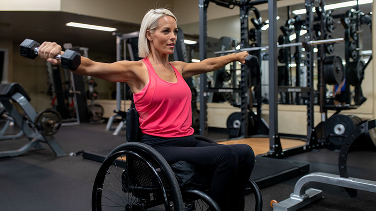 Adaptive athlete in a wheelchair lifting weights.