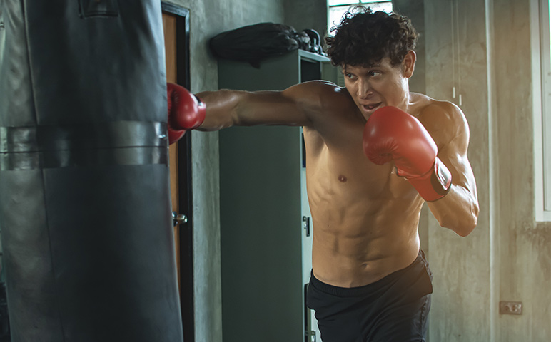 man hitting black boxing bag with red gloves